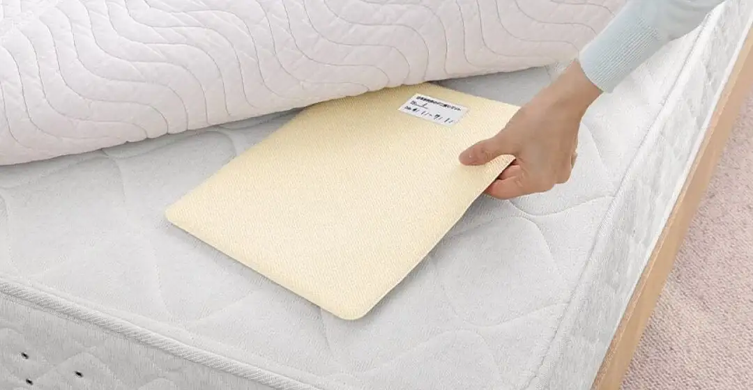 画像：ダニ捕りマットをベッドに差し込む