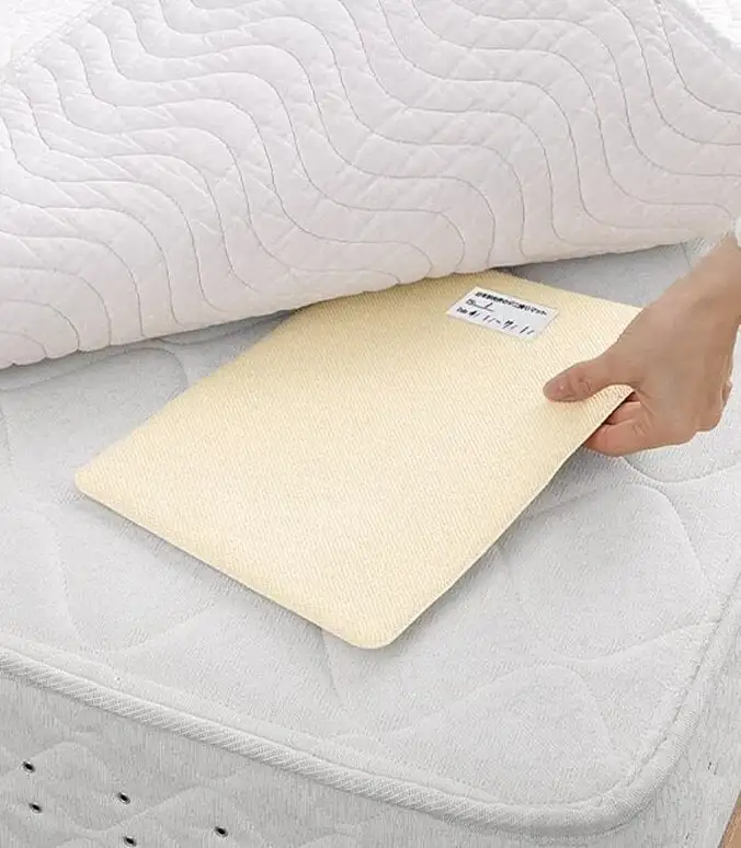 画像：ダニ捕りマットをベッドに差し込む