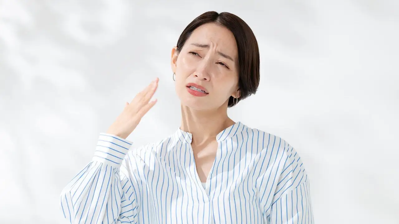 画像：室内で熱中症にかかる。女性が暑がっている