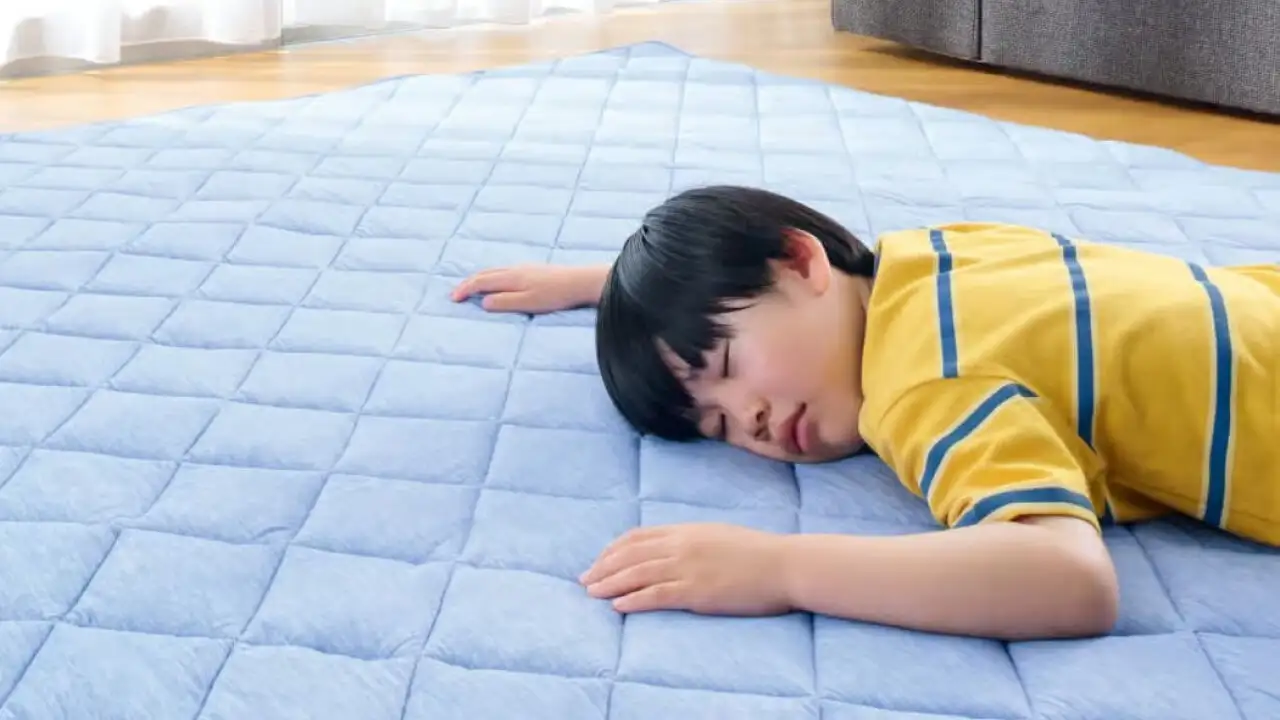 床に商品『ひんやり5層ラグ』を敷いた上に、小学生くらいの男の子がうつ伏せに寝ている