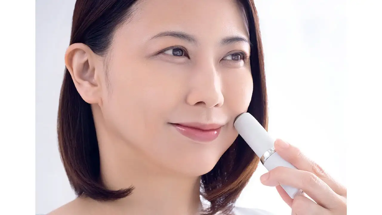 シェーバーを左手に持ち、顔に当てている女性