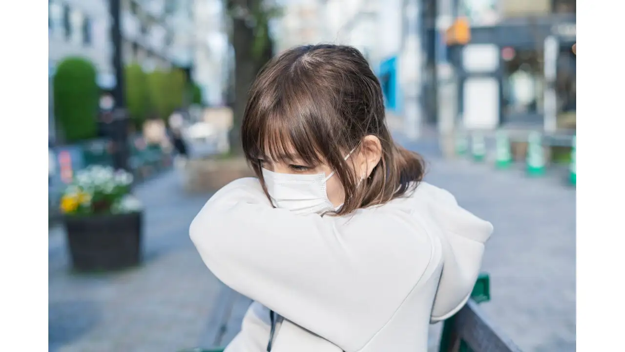 肘の内側に向かって咳をする女性